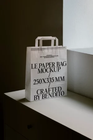 White paper bag mockup with handles, styled on a cabinet with natural lighting, perfect for branding takeaway packaging or retail goods.