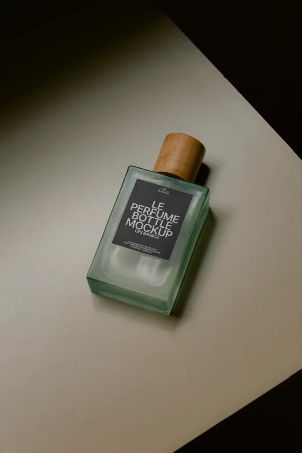 Elegant rectangular glass perfume bottle with wooden cap, shot in moody lighting on a beige surface.