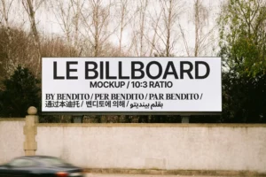 Horizontal roadside billboard mockup with a 10:3 ratio, displayed in a natural outdoor setting with a moving car in front. Design by Bendito Mockup.