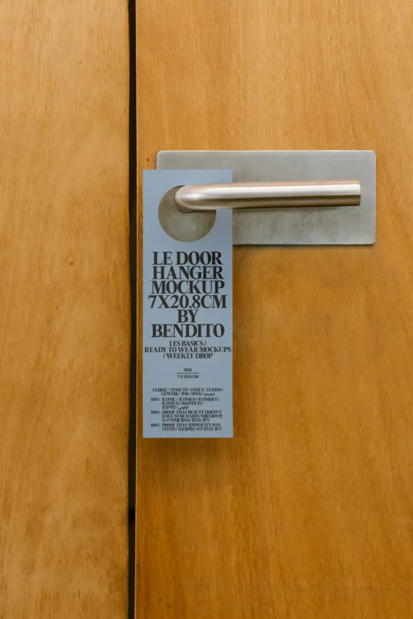 Door hanger mockup hanging from a metallic handle on a wooden door. Designed for 7 × 20.8 cm formats, perfect for hospitality or campaign messaging.
