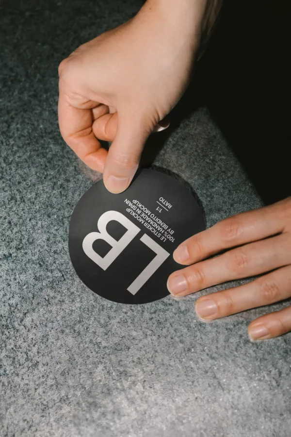 Circular sticker mockup being peeled off a textured surface. Features a 1:1 ratio design, perfect for branding, labels, or packaging seals.
