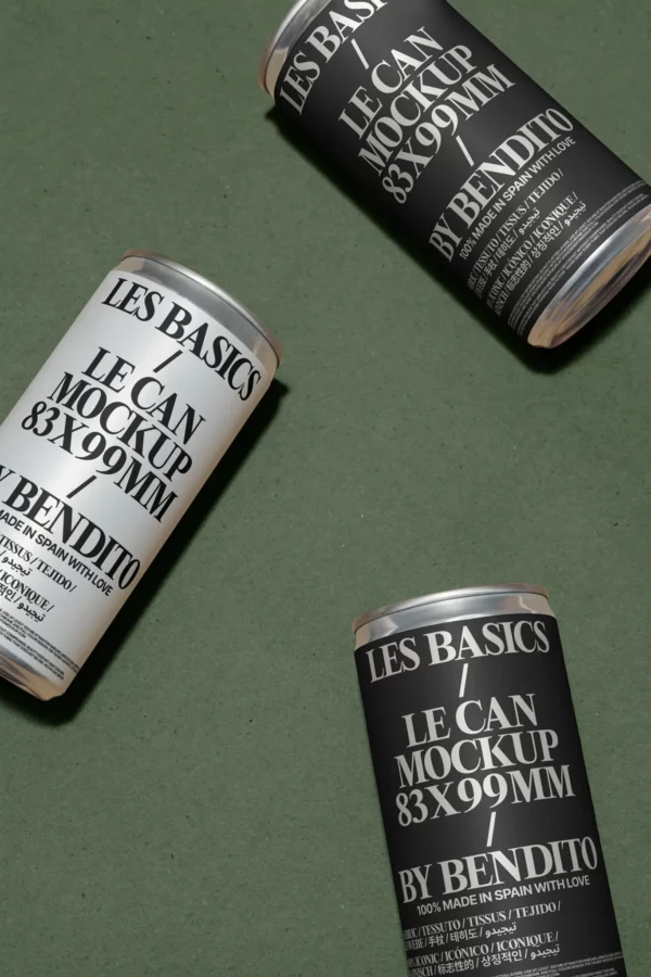 Three cans with minimalist black and white labels reading LES BASICS LE CAN MOCKUP 83X99MM BY BENDITO are arranged diagonally on a textured green surface.