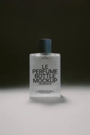 A frosted glass perfume bottle with a black cap stands upright on a gray surface, featuring bold black text that reads Le Perfume Bottle Mockup Les Basics on the front.