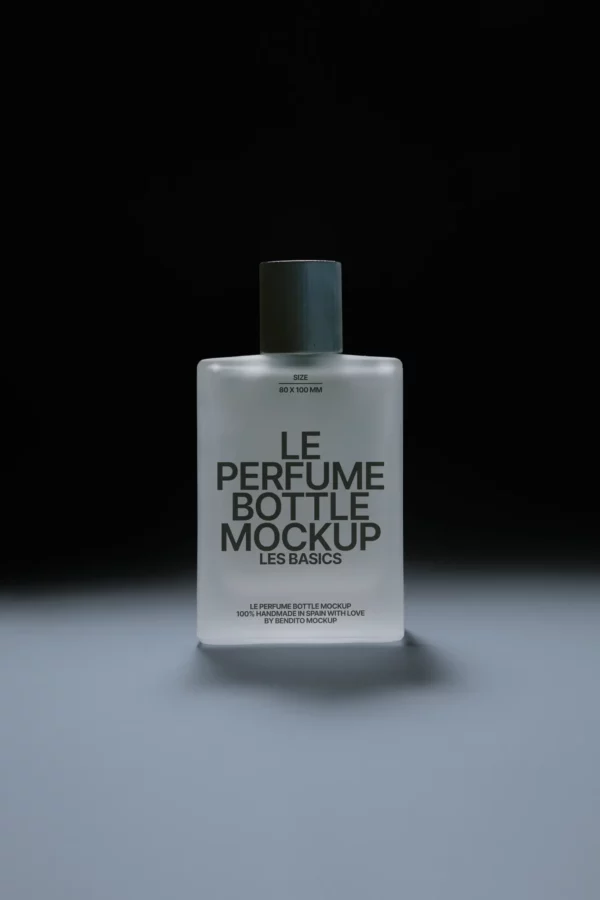 A frosted glass perfume bottle with a dark cap is centered on a grey surface against a dark background. The bottle is labeled Le Perfume Bottle Mockup Les Basics in bold black letters.