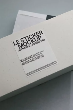 A rectangular white box with a minimalist label reading LE STICKER MOCKUP, LES BASICS | BY BENDITO in bold, black text, photographed on a grey background.