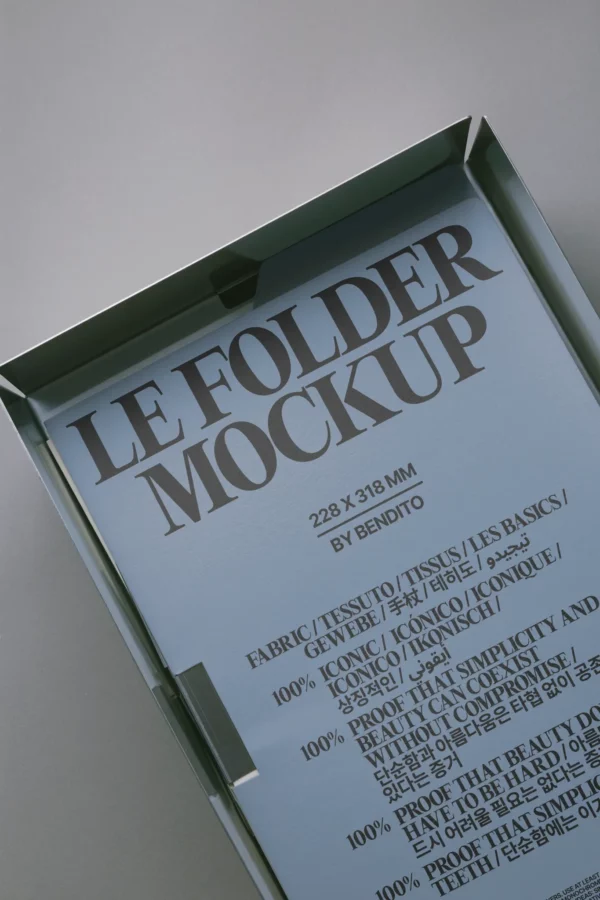 A close-up of a blue folder mockup box with bold gray text reading LE FOLDER MOCKUP 228 x 318 mm BY BENDITO and smaller text in various languages describing the folder.