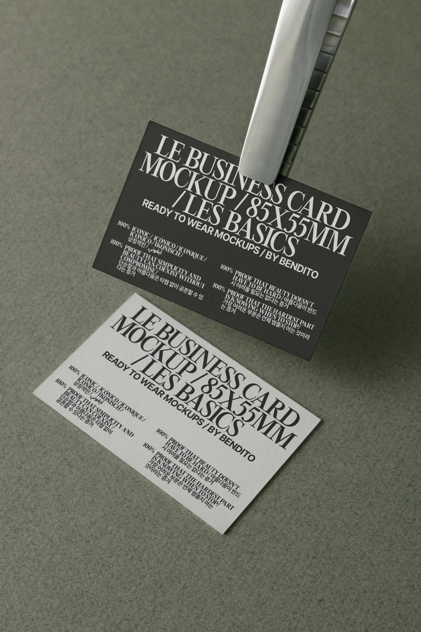 A black business card and a white business card with identical text are displayed on a gray surface. One card is clipped upright in a metal holder, while the other lies flat on the surface.