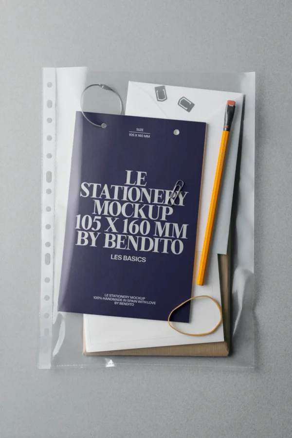 A clear plastic folder containing a navy blue notepad, a pencil, a paperclip, rubber band, and white sheets of paper, all arranged neatly on a gray surface.